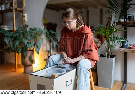 Young Woman Wearing Glasses Learning How To Throw Clay On Pottery Wheel, Visiting Ceramics Mastercla