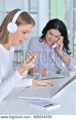 Young Businesswoman In Headphones Working In Modern Office With Her Olleague