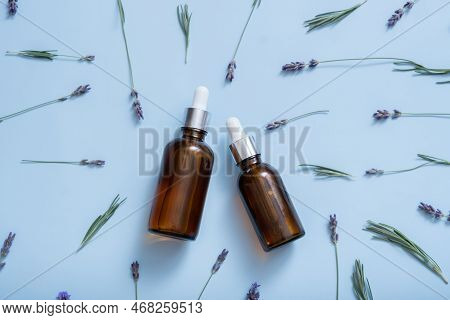 Dropper Bottles With Lavender Flowers Pattern On Colored Background Top View