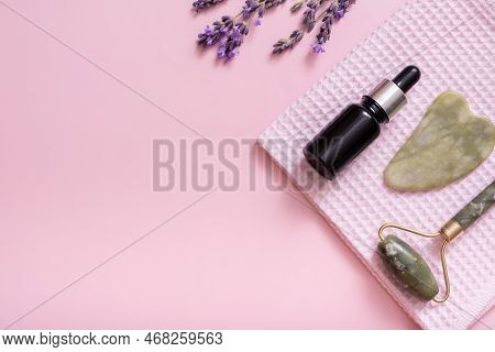 Massager For Face Skin, Towel And Dropper Bottle With Lavender Flowers On Colored Background Top Vie