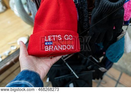 St. Augustine, Florida - December 30, 2022: Hand Holds A Lets Go Brandon Beanie Hat, While Shopping.