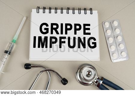 Medical Concept. On A Gray Surface, A Syringe, A Thermometer, A Stethoscope, A Blister And A Notepad