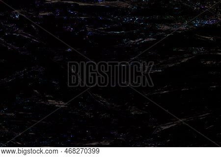 Black Color Plastic Wrap Background. Dark Crumpled Wrinkled Plastic Cellophane. Reflecting Blue Ligh