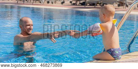 Egypt. Hurghada. 04.14.2021 Father And Child Have Fun In The Pool In Clear Weather. A Father Teaches