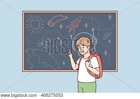 Joyful Boy With Backpack Behind Back Stands Near Blackboard Depicting Universe With Spaceships And P
