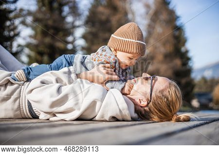Happy Family. Young Mother Playing With Her Baby Boy Infant Oudoors On Sunny Autumn Day. Portrait Of