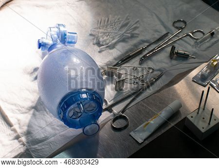 On The Table Among The Surgical Instruments Lies An Ambu Bag. The Oxygen Bag Is Intended For Resusci