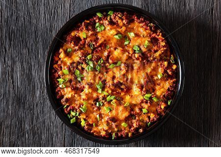Cajun Beef Cornbread Casserole Topped With Melted Red Cheddar Cheese And Scalions In Baking Dish On 