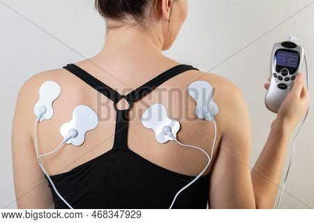 Acupuncture Electronic Massager On The Girl's Back To Relax Muscles And Relieve Back Pain. Home Phys