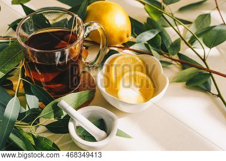 Cup Tea With Brewing Inside, Lemon, Eucalyptus Leaves On White Background.