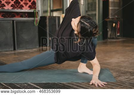 Woman Yogi And New Teacher Young Adult Doing A Twisted Skandasana Pose With One Arm To Ceiling Weari