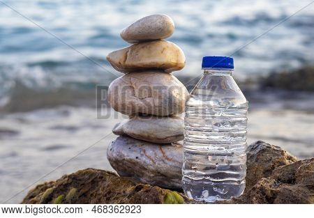 Pebbles In Pyramid One Over Another And Bottle With Drinking Water