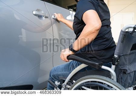 Asian Woman Folding And Lift Up Wheelchair Into Her Car. Accessibility Concept.