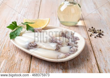 Fresh Squid Tubes On A Plate Over Wooden Table. Small Calamary Fillet, Lemon And Olive Oil Prepared 