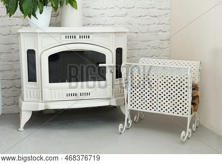 Little Beautiful Fireplace On Wood And Coal, White Color Located In Room With A Metal Wrought Pallet