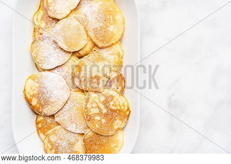 Flat Lay. Freshly Made Small Pancakes On A Kefir Base Garnished With Powdered Sugar.