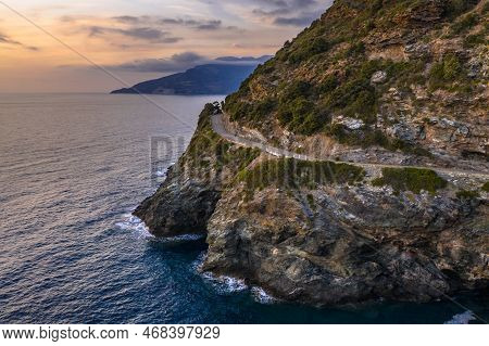 Winding Road Along Rocky Coast Of Cap Corse Peninsula On Corsica Island At Sunset, France