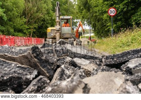 Excavator With Hydraulic Jack Hammer  Breaking Asphalt In Preparation For Drainage Works Close Up An
