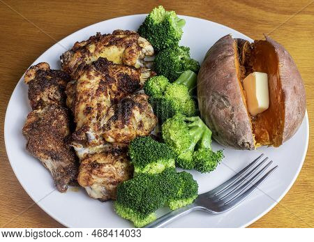 Chicken Wings Served With Broccoli And A Sweet Potato.