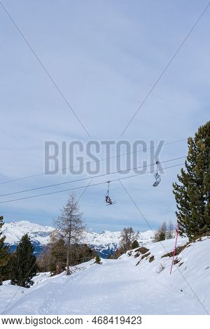 Focus On Two Chairlifts In Winter With Undefined Skiers In Ski Resort St. Luc In Wallis Switzerland.