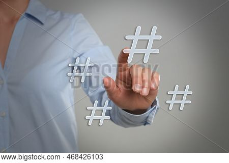 Hashtag Concept. Woman Pointing At Sign On Light Grey Background, Closeup