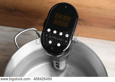 Sous Vide Cooker In Pot On White Wooden Table, Closeup. Thermal Immersion Circulator