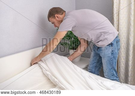 A Man Makes His Cozy Bed With Fresh Bright White Bed Linen. Making The Bed With Fresh Bed Linen By W