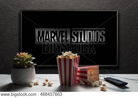 Tv Screen Playing Marvel Studios Movie. Tv With Remote Control, Popcorn Boxes And Home Plant. Moscow