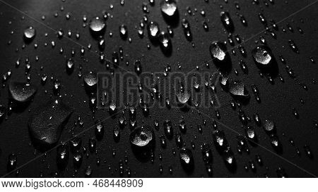 Round Drops Of Water On Dark Background. Through Transparent Drops Of Water Pass Rays Of Light. View