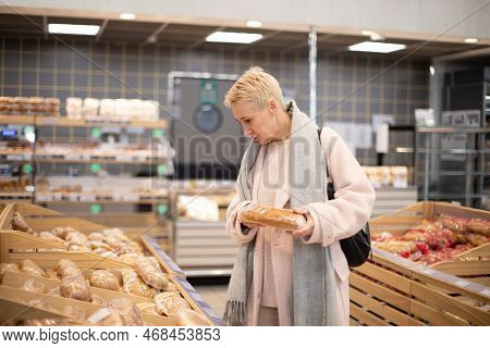 Smiling Senior Mature Woman Choosing Bread And Baking In Grocery Section Of Supermarket At The Baker