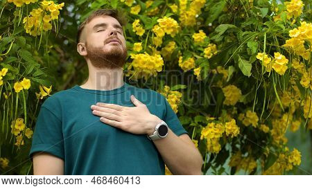 Portrait Of Happy Handsome Bearded Guy, Young Positive Man With Beard Is Smelling Beautiful Yellow F