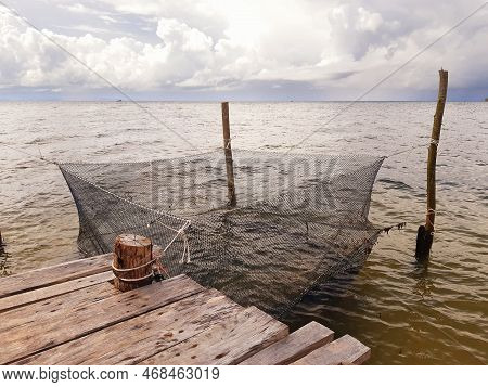Net For Fish Breeding In Gray Waters Of The Mekong. Fish Cage Of An Aquaculture In The Sea. Fish Far