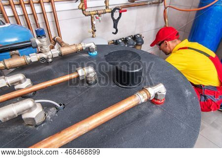 Aerial View Of Tank-type Hot Water Heater Inside Residential Boiler Room. Plumber Performing Heating