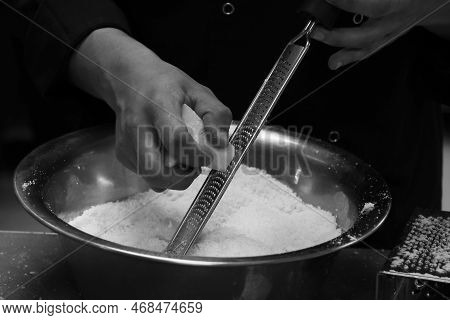 Chef Grating Parmesan Cheese With Fine Grater  In Close Up In Kitchen