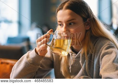 Portrait Of A Joyful Teengirl Enjoying A Cup Of Tea At Cafe. Smiling Beautiful Girl Drinks Hot Tea I
