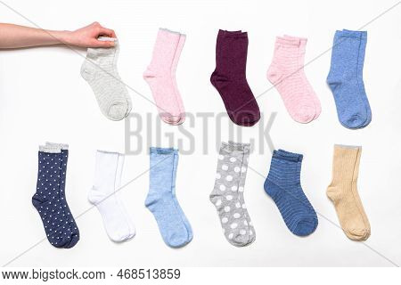 Female Hand Holding Socks Among Women's Cotton Socks Set On White Background. Fashionable Socks Stor