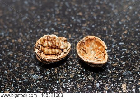 A Ripe Open Walnut In Its Shell On A Black Table.