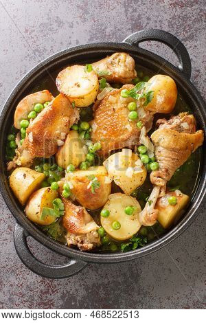Homemade Baked Chicken Vesuvio With Peas And Potatoes Closeup On The Black Pan On The Table. Vertica