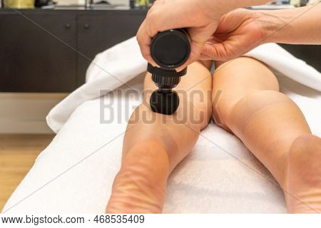 Professional Masseuse Massaging The Calf Muscles Of A Womans Leg Using The Massage Gun. . High Quali