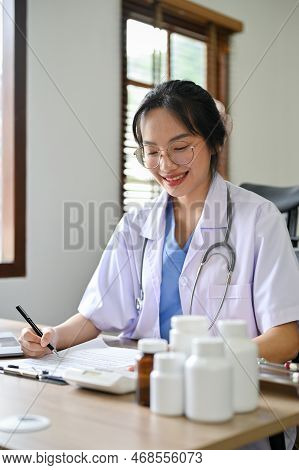 Professional Asian Female Doctor Or Pharmacist Working At Her Desk In The Clinic Office.