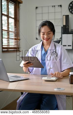 Beautiful Asian Female Doctor Using Calculator, Estimating Surgery Cost For Her Patient