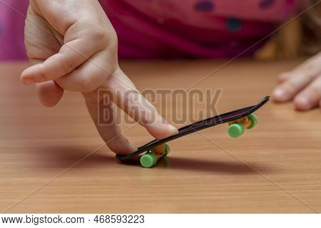 Children\'s Fingers Do Fingerskate Tricks On A Wooden Table, Close-up, Selective Focus.