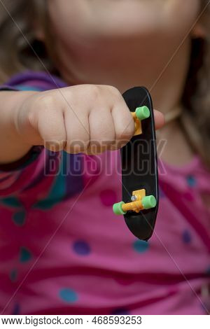The Girl Holds A Fingerboard In Her Hand, Close-up, Selective Focus.