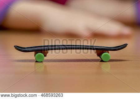 A Fingerboard On A Wooden Surface, Children\'s Hands In The Background Out Of Focus, Close-up, Finge