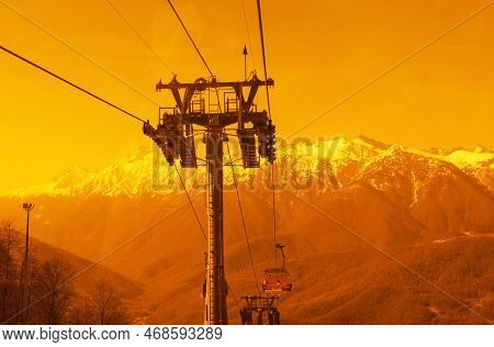 Chair Lift Going Down Against The Backdrop Of Snow Capped Mountains In Yellow Tone Alpine Skiing And