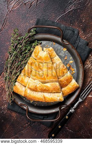 Slices Of Baked Round Borek Cheese Pie In Kitchen Tray With Herbs. Dark Background. Top View.