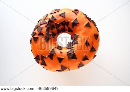 Halloween Donut With Orange Frosting And Chocolate Triangles As A Sweet Decorative Topping. Children