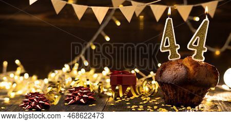 Number 44 Golden Festive Burning Candles In A Cake, Wooden Holiday Background. Forty Four Years From