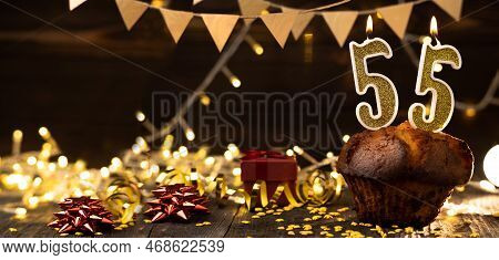Number 55 Golden Festive Burning Candles In A Cake, Wooden Holiday Background. Fifty-five Years Sinc
