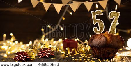Number 57 Golden Festive Burning Candles In A Cake, Wooden Holiday Background. Fifty-seven Years Sin